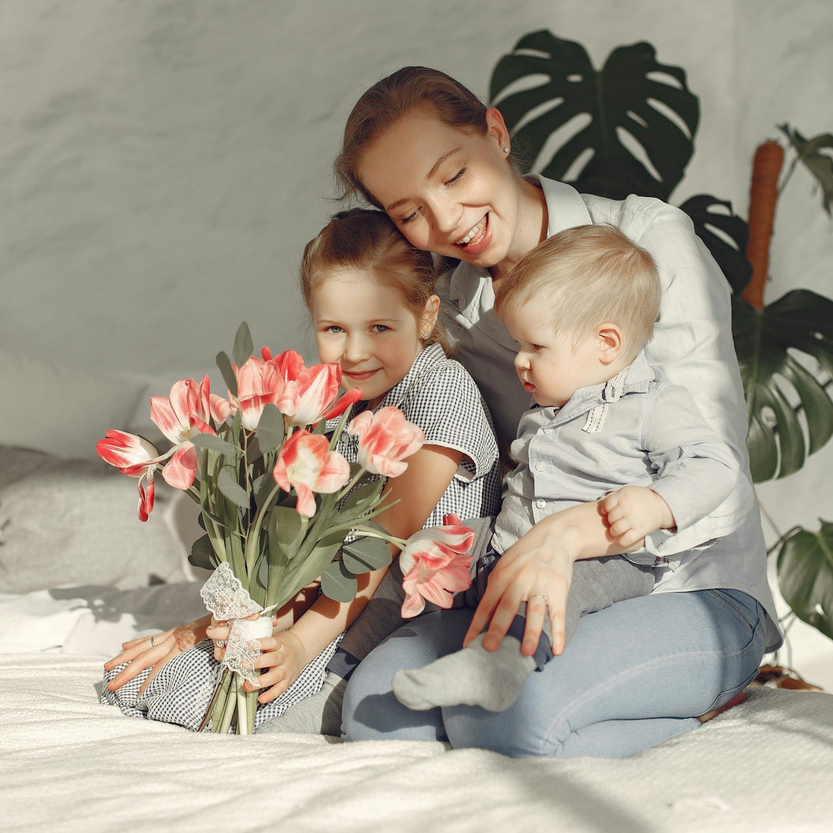 Mother and children enjoying a happy moment with flowers in a cozy bedroom.